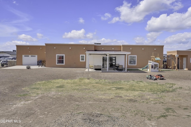 rear view of property featuring a patio area, stucco siding, and a playground