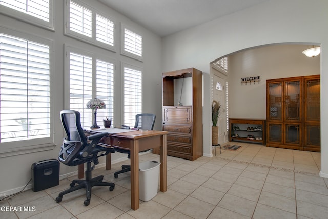 office with light tile patterned flooring, plenty of natural light, and arched walkways