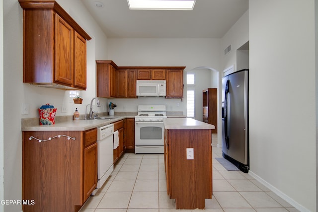 kitchen featuring visible vents, light countertops, brown cabinets, white appliances, and a sink