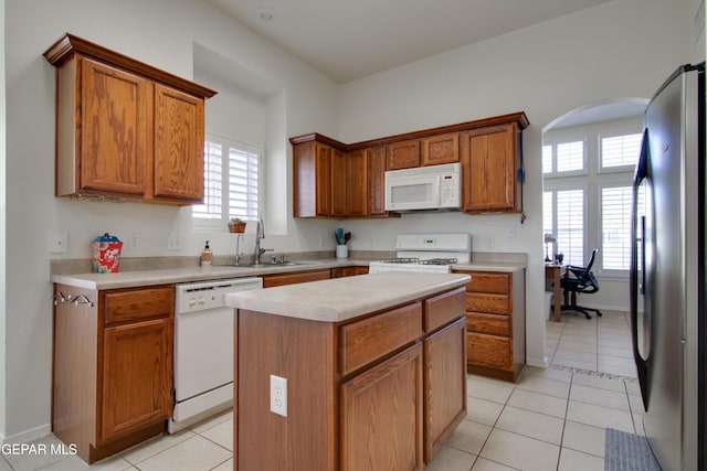 kitchen featuring light tile patterned flooring, white appliances, light countertops, and a sink