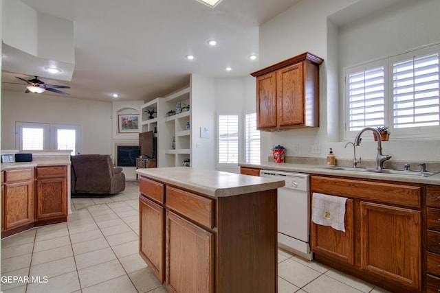 kitchen with a glass covered fireplace, light tile patterned flooring, white dishwasher, and a sink