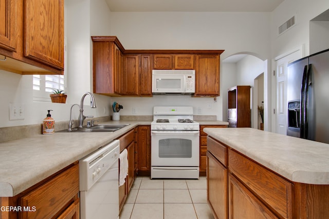 kitchen featuring white appliances, visible vents, brown cabinets, and a sink