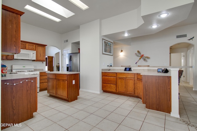 kitchen with white appliances, arched walkways, a peninsula, and light countertops