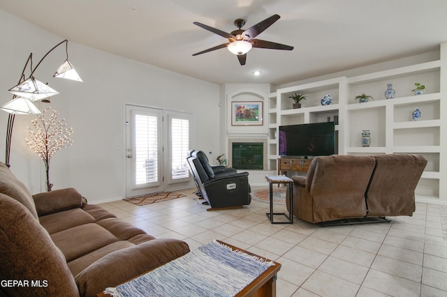 living room with light tile patterned floors, built in features, baseboards, and ceiling fan