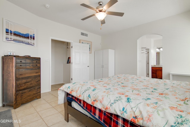 bedroom featuring light tile patterned floors, visible vents, arched walkways, and a ceiling fan