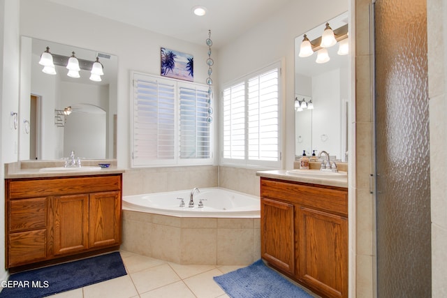 bathroom featuring tile patterned flooring, two vanities, a bath, and a sink