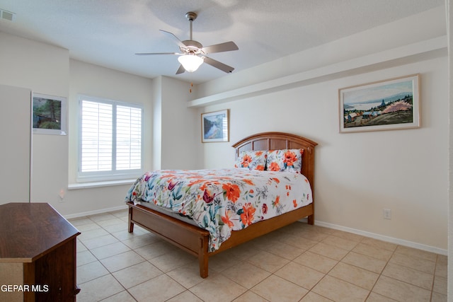 bedroom featuring a ceiling fan, light tile patterned floors, visible vents, and baseboards