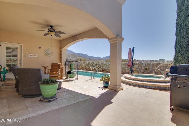 view of patio featuring a fenced in pool, ceiling fan, fence, a mountain view, and an in ground hot tub