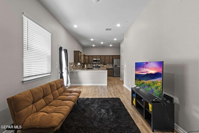 living area with recessed lighting, visible vents, baseboards, and light wood-style floors