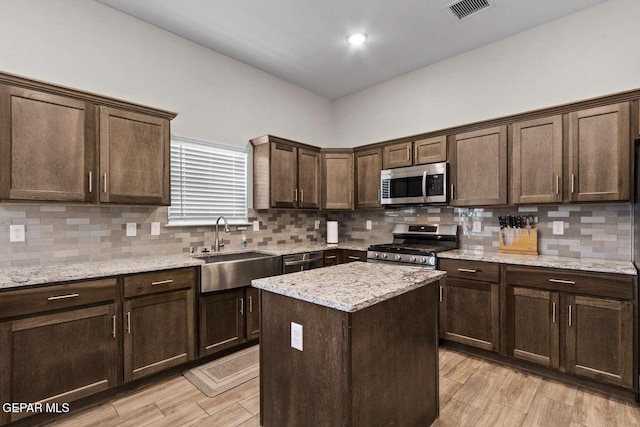 kitchen featuring a sink, tasteful backsplash, dark brown cabinetry, and appliances with stainless steel finishes