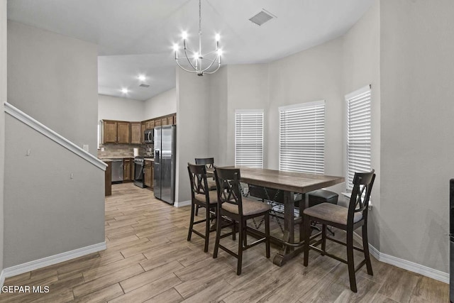 dining room featuring baseboards, visible vents, light wood-type flooring, and a chandelier