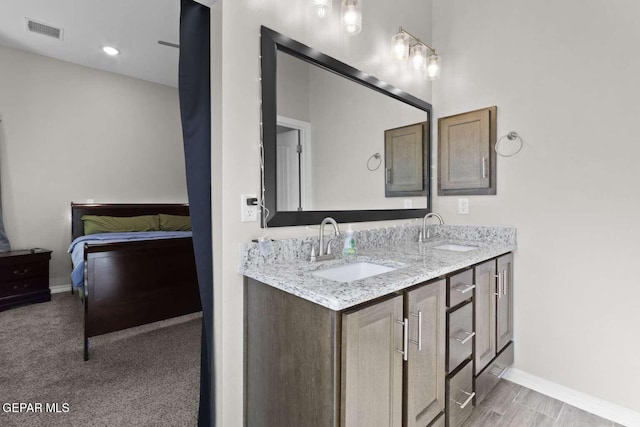 ensuite bathroom with double vanity, visible vents, baseboards, and a sink