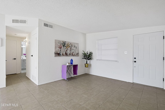 foyer with light tile patterned floors, visible vents, and a textured ceiling