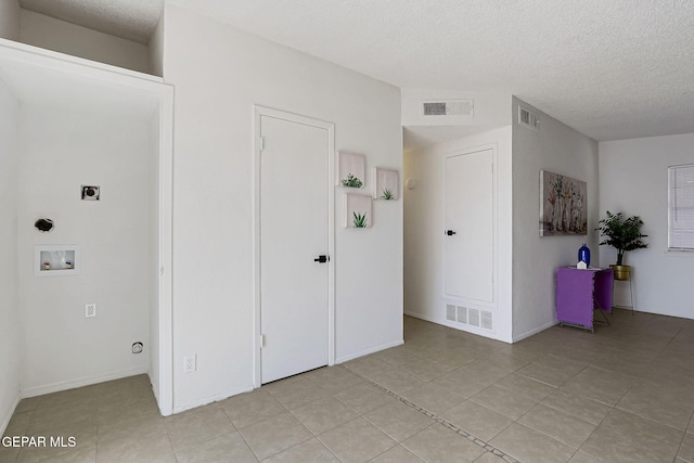 interior space featuring light tile patterned floors, visible vents, and a textured ceiling