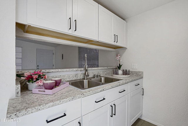 kitchen featuring light countertops, white cabinets, and a sink