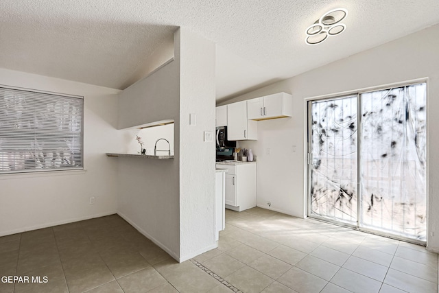 kitchen with light tile patterned floors, white cabinets, and vaulted ceiling