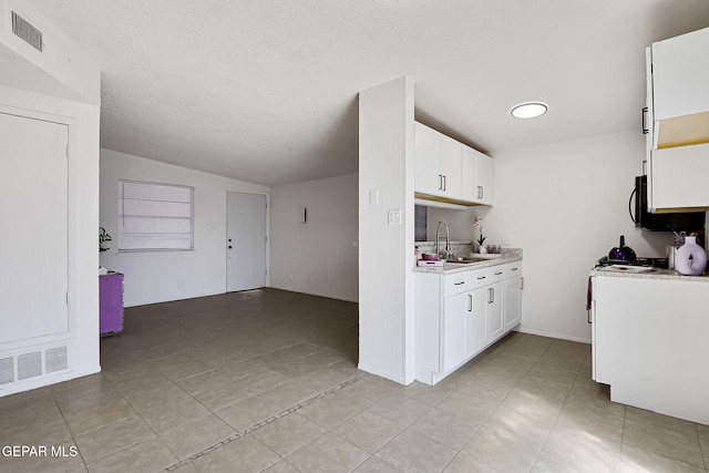 kitchen with visible vents, white cabinets, light countertops, and a sink