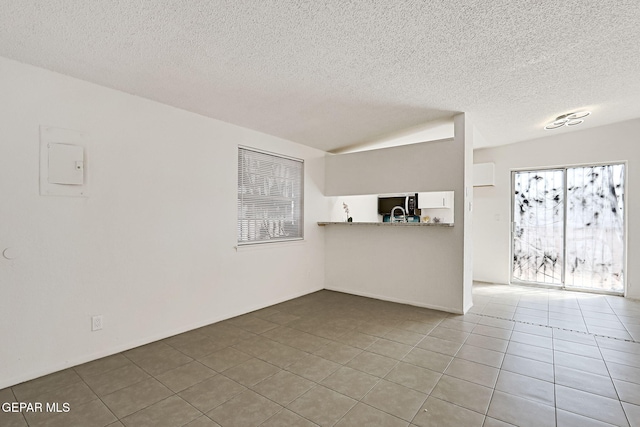 unfurnished living room with tile patterned flooring and a textured ceiling