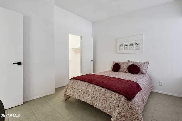 bedroom featuring baseboards, a textured ceiling, and tile patterned flooring