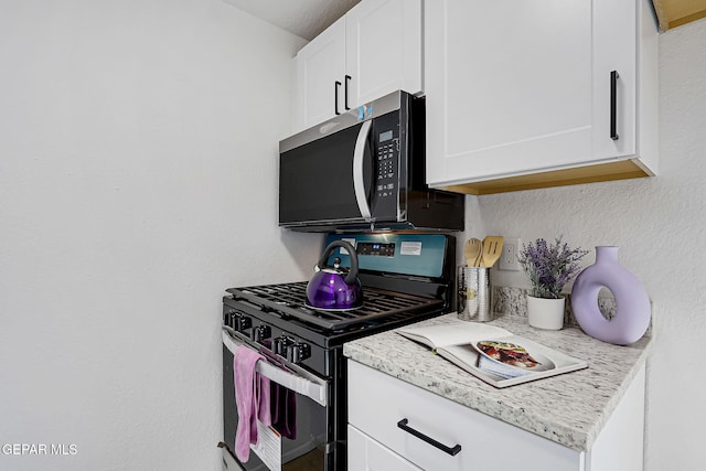 kitchen with white cabinets, stainless steel appliances, and a textured wall