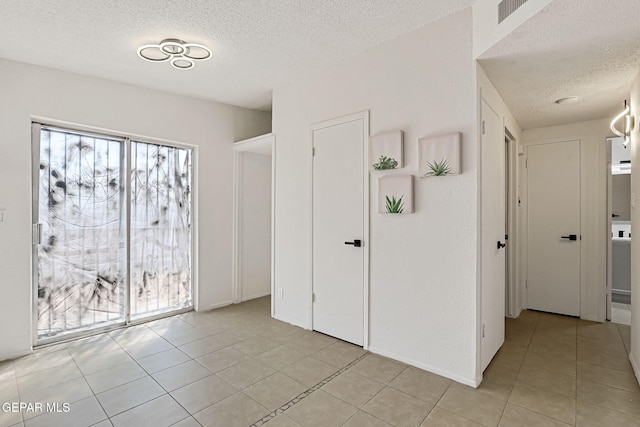 interior space with light tile patterned flooring, visible vents, and a textured ceiling