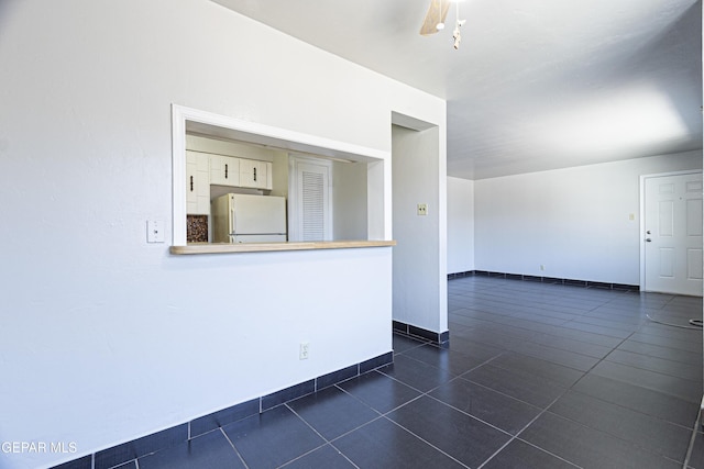 empty room featuring dark tile patterned flooring and baseboards