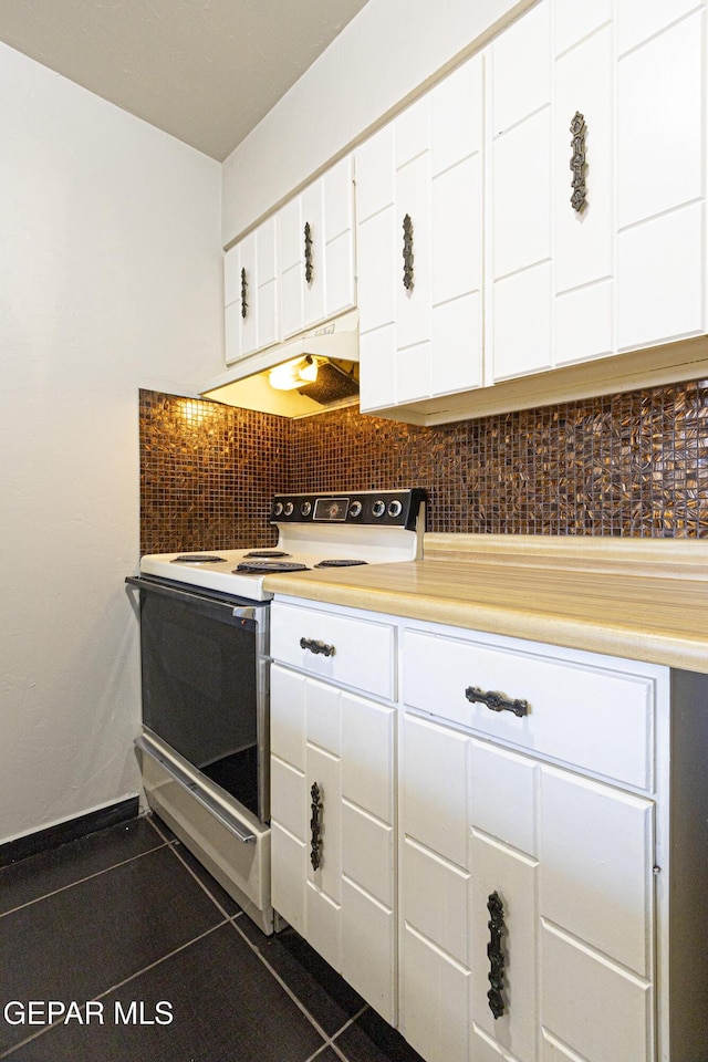 kitchen featuring electric range, dark tile patterned floors, under cabinet range hood, white cabinetry, and light countertops