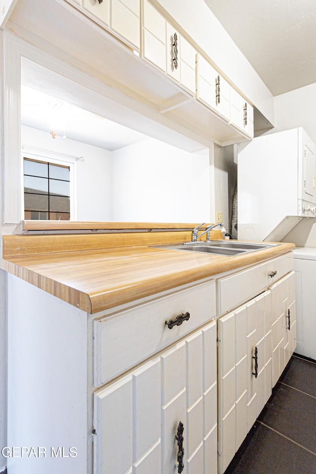 kitchen with a sink, wooden counters, and white cabinetry