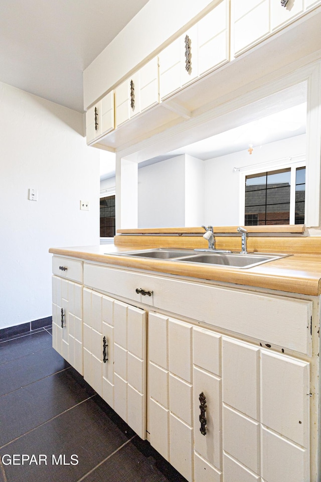 kitchen featuring white cabinetry, light countertops, baseboards, and a sink