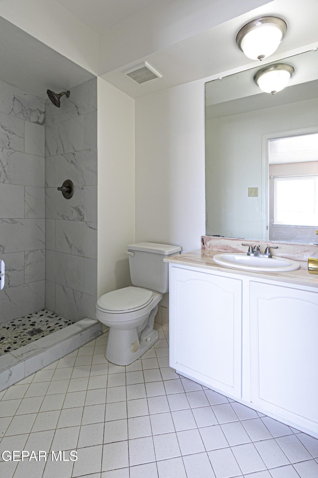 bathroom featuring vanity, toilet, visible vents, and a tile shower