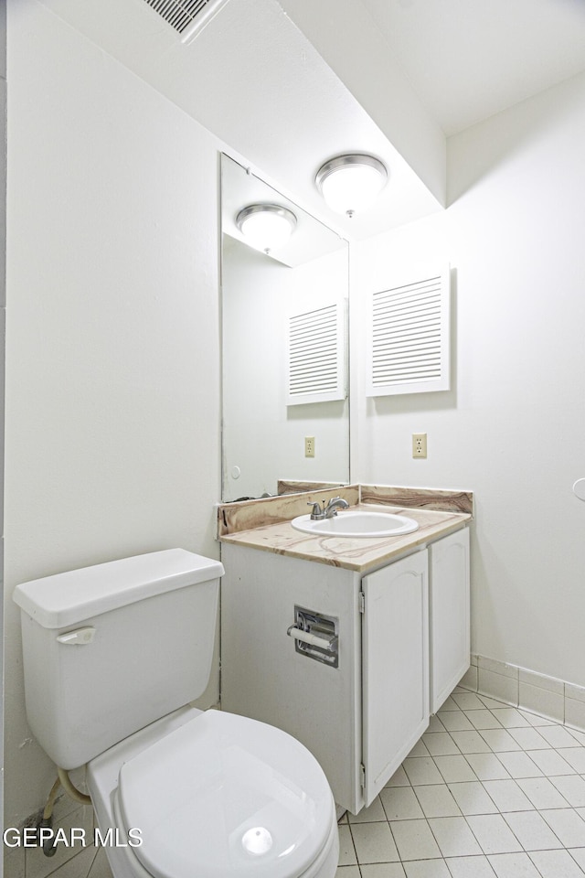 half bath with tile patterned flooring, toilet, vanity, and baseboards