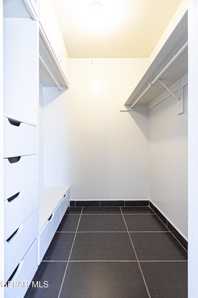 walk in closet with dark tile patterned floors