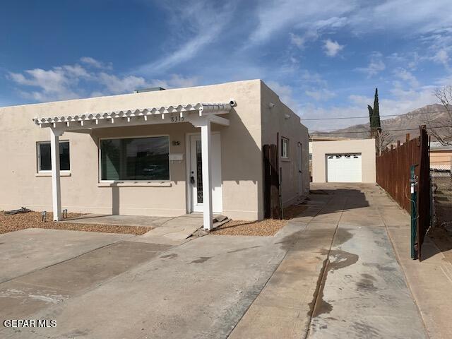 view of property exterior featuring stucco siding, an outbuilding, concrete driveway, and fence