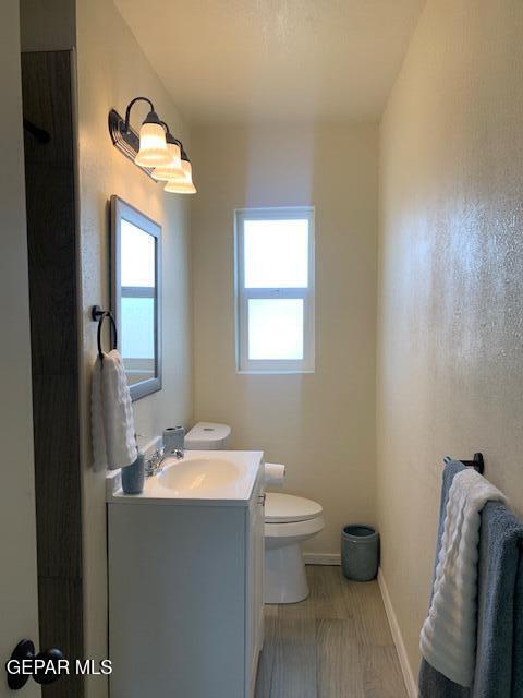 bathroom with vanity, toilet, wood finished floors, and baseboards