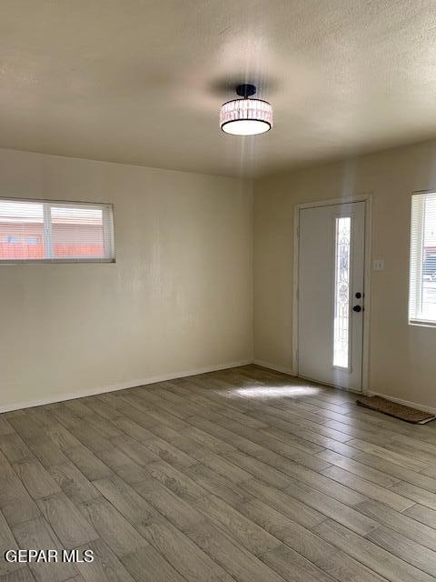 foyer with wood finished floors, baseboards, and a textured ceiling