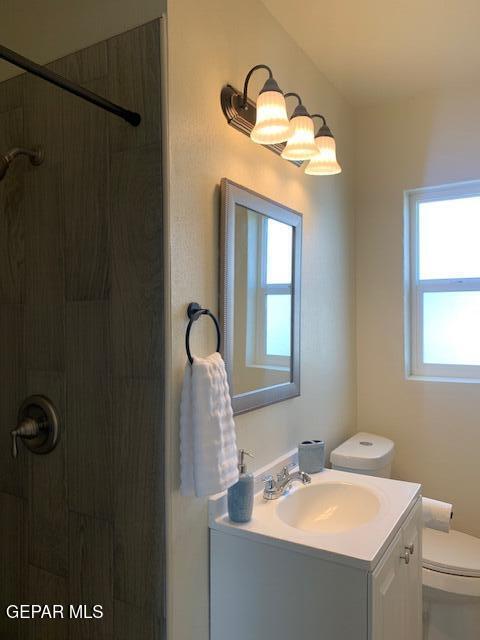 bathroom featuring vanity, toilet, and tiled shower