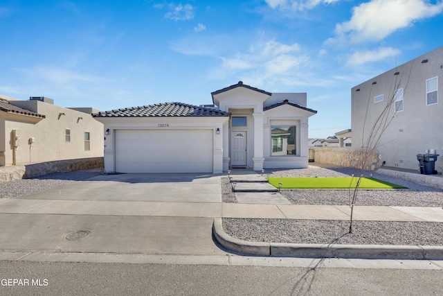 view of front facade with a tiled roof, stucco siding, driveway, and an attached garage