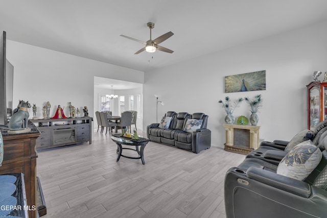 living room with ceiling fan with notable chandelier and light wood-style flooring