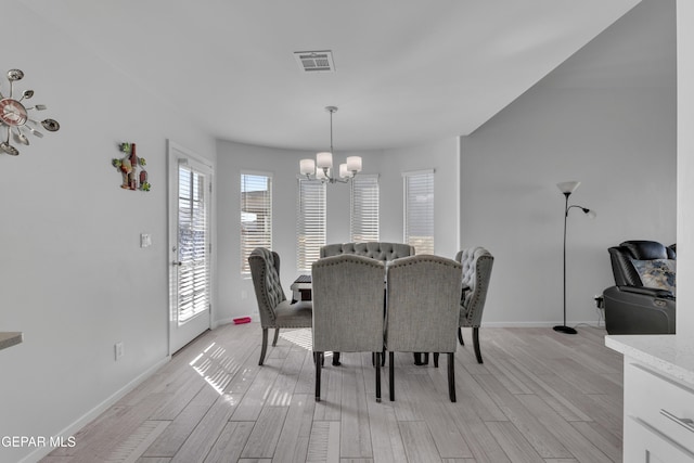 dining area featuring visible vents, baseboards, a chandelier, and light wood finished floors