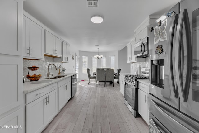 kitchen featuring visible vents, a sink, light countertops, appliances with stainless steel finishes, and a notable chandelier