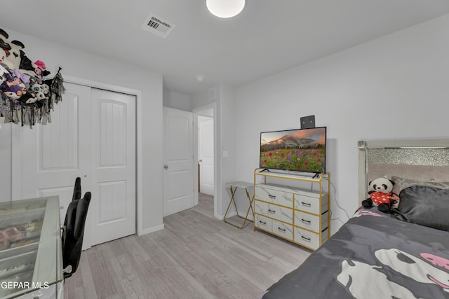 bedroom featuring light wood-style flooring, baseboards, visible vents, and a closet