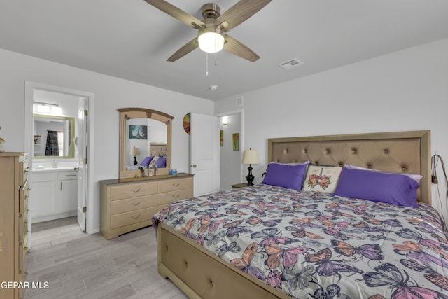 bedroom featuring light wood finished floors, visible vents, connected bathroom, and ceiling fan