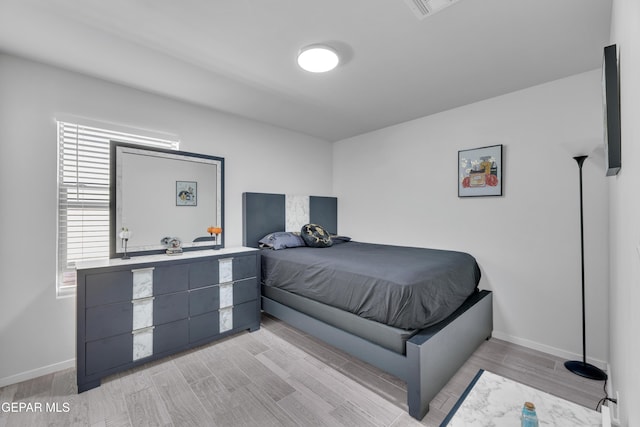 bedroom featuring visible vents, light wood-type flooring, and baseboards