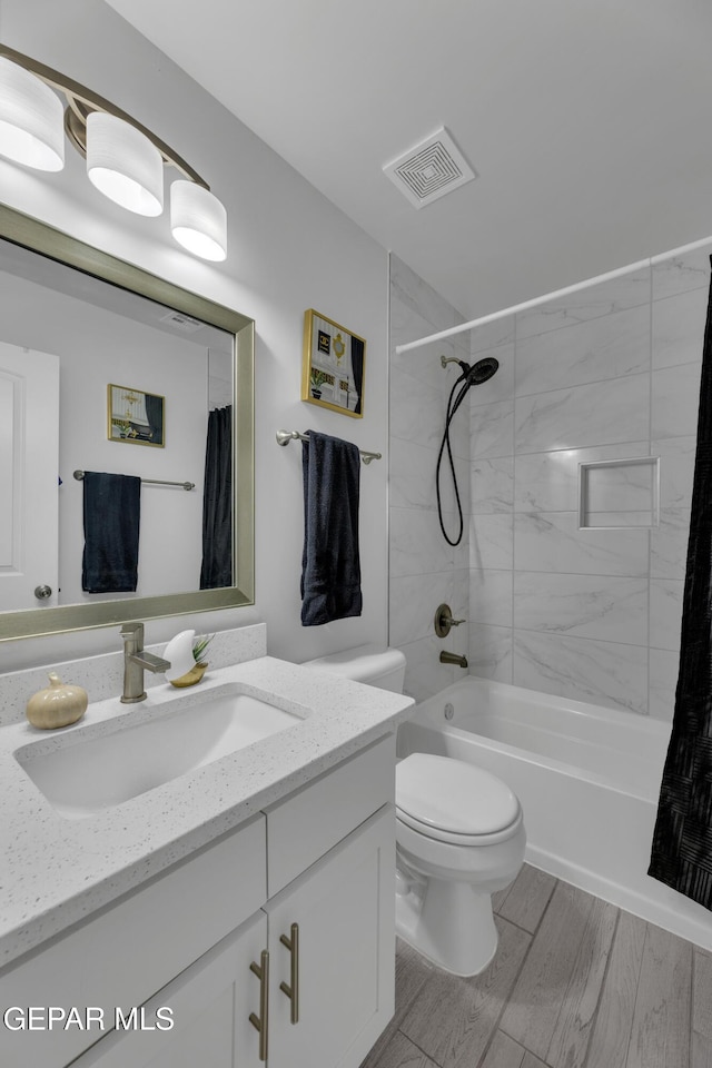 bathroom with vanity, wood finished floors, visible vents, shower / bath combo, and toilet