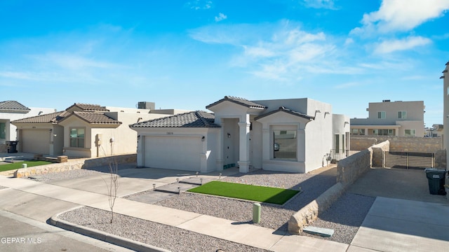 view of front of house with stucco siding, driveway, a tile roof, fence, and an attached garage