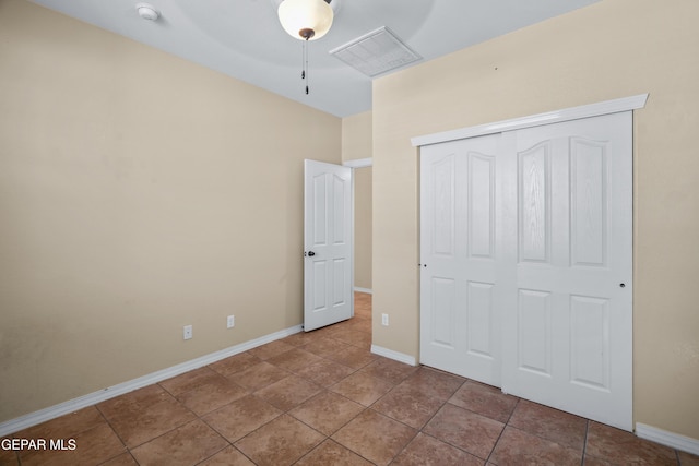 unfurnished bedroom with a closet, visible vents, tile patterned floors, and baseboards