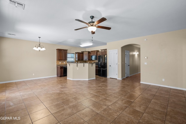 kitchen featuring visible vents, black appliances, ceiling fan with notable chandelier, open floor plan, and arched walkways