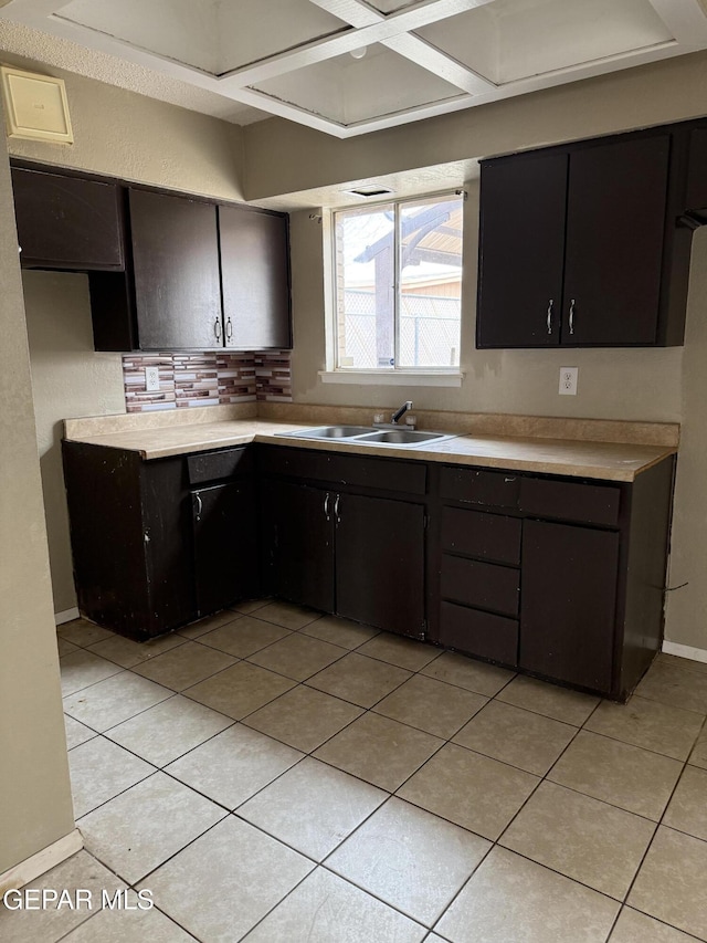 kitchen with light countertops, light tile patterned floors, baseboards, and a sink