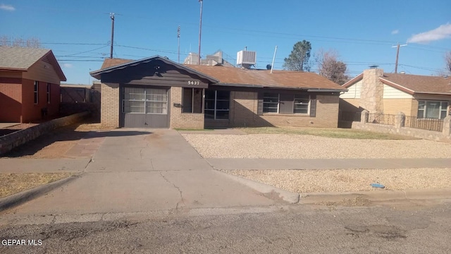 view of front of home featuring brick siding, driveway, central AC, and fence