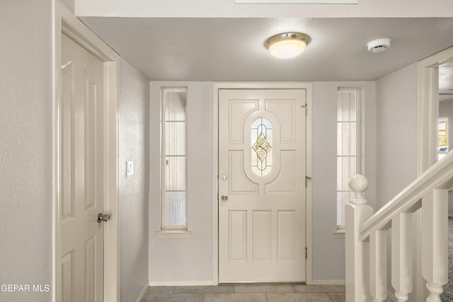 foyer entrance with light tile patterned floors and baseboards